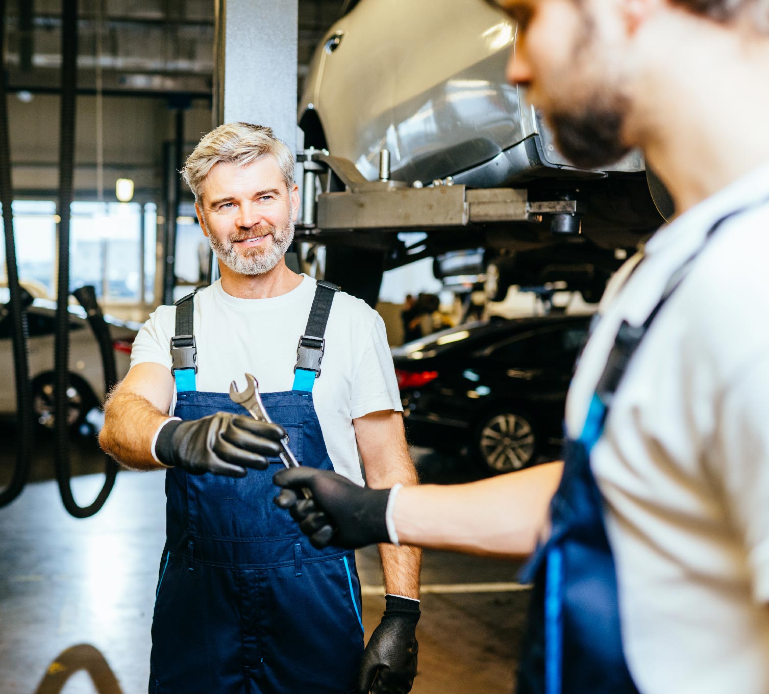 KFZ Mechaniker unterstützen sich bei der Reparatur von Auto in Hamburg